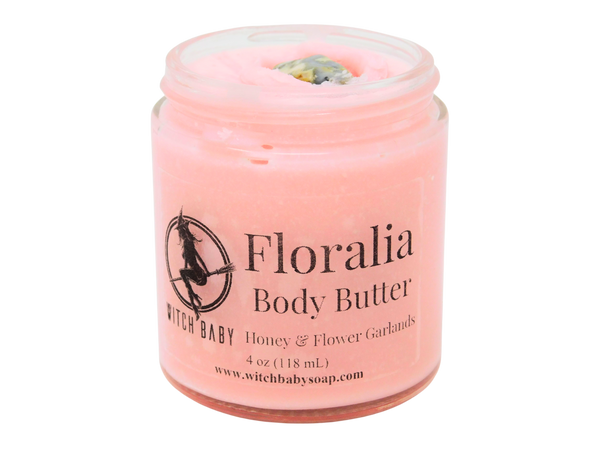 Pink body butter packaged in a 4 oz glass jar with a crazy lace agate crystal on top and a clear label that reads: Floralia Body Butter. Honey & Flower Garlands.