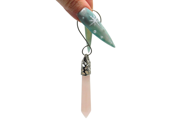 Hand holding a crystal with a decorative handle against a white background