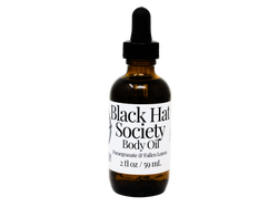 2 oz brown glass dropper bottle with white label that reads: Black Hat Society Body Oil. Pomegranate & Fallen leaves. 