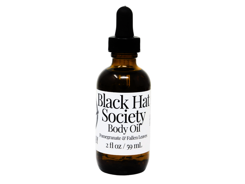 2 oz brown glass dropper bottle with white label that reads: Black Hat Society Body Oil. Pomegranate & Fallen leaves. 