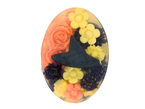 oval soap filled with orange, yellow, and purple flowers surrounding a black witch hat
