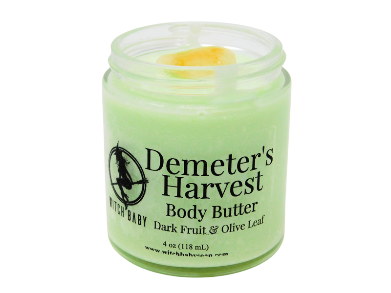 pastel green body butter in 4 oz glass jar with a clear label that reads: Demeter's Harvest Body Butter. Dark Fruit & Olive Leaf. 