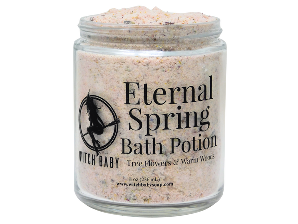 flower filled bath potion in glass jar with label that reads eternal spring bath potion. tree flowers  & warm woods.