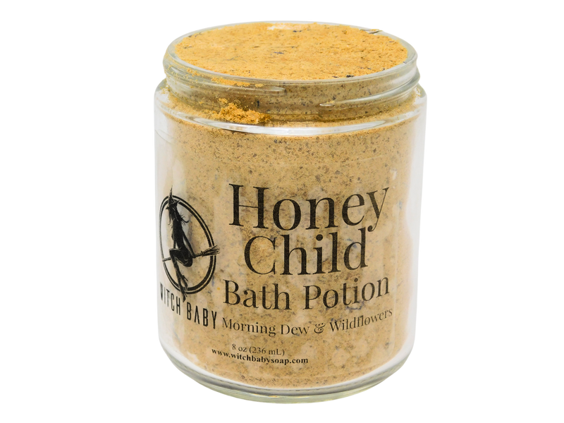 8 oz glass jar filled with dark yellow bath potion with a clear label that reads: Honey Child Bath Potion. Morning Dew & Wildflowers.