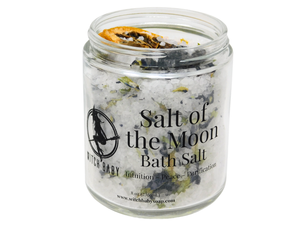 bath salt blended with butterfly pea flowers and topped with lemon and moonstone packaged in 8 oz glass jar with clear label that reads Salt of the Moon Bath Salt. Intuition - Peace - Purification.