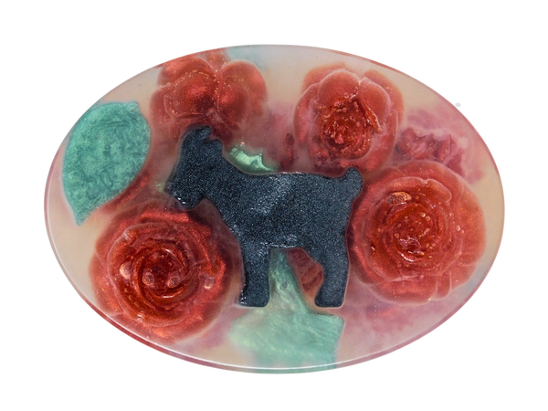 clear oval soap with red roses, grean leaves, and a black goat inside. 
