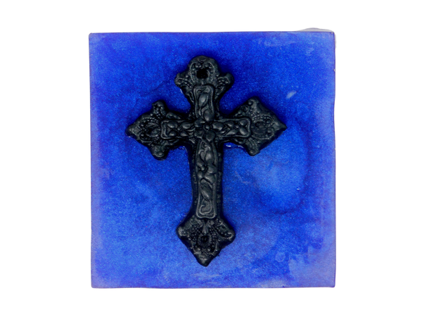 A squared shaped purple soap that smells like violets and sugar topped with a black cross.