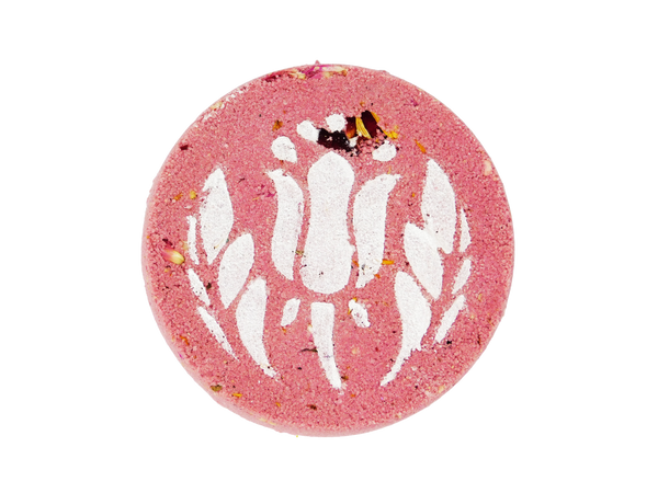 pink circular shaped rose filled bath bomb with white air brush of a flower on top