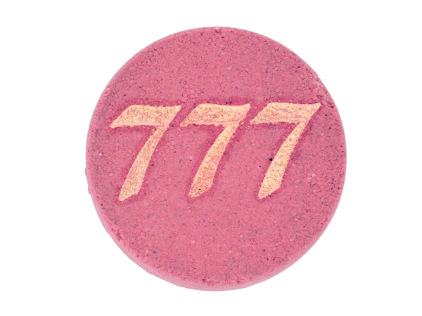 pink circular bath bomb with 777 in gold mica on front