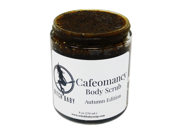 photo of cafeomancy body scrub pictured in 8 oz (236 mL) glass jar. Scrub is a dark brown with orange hues and a wet pumpkin puree texture speckled with sugar and coffee grinds. Label reads: Cafeomancy Body Scrub. Autumn Edition.