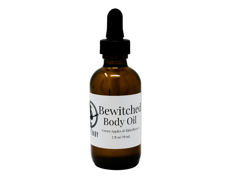 Bewitched Body Oil packaged in a 2 oz glass dropper bottle with a white label that reads: Bewitched Body Oil. Green Apples & Elder Flowers. 