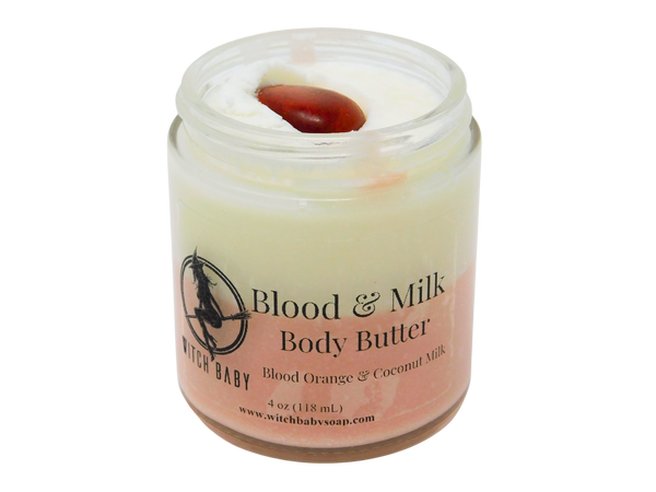 4 oz glass jar containing two color body butter. Top is white and bottom is pink. Topped with red jasper. Label says blood and milk body butter, blood orange and coconut milk.