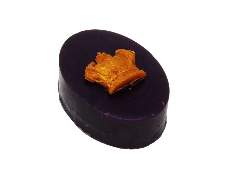 Side view of deep plum colored oval soap with a gold crown on top.