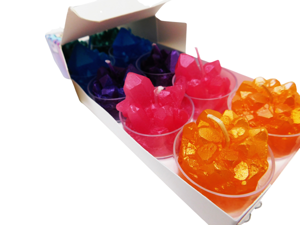 Crystal shaped candles inside of small plastic container. Green, blue, purple, pink, and orange pictured. 