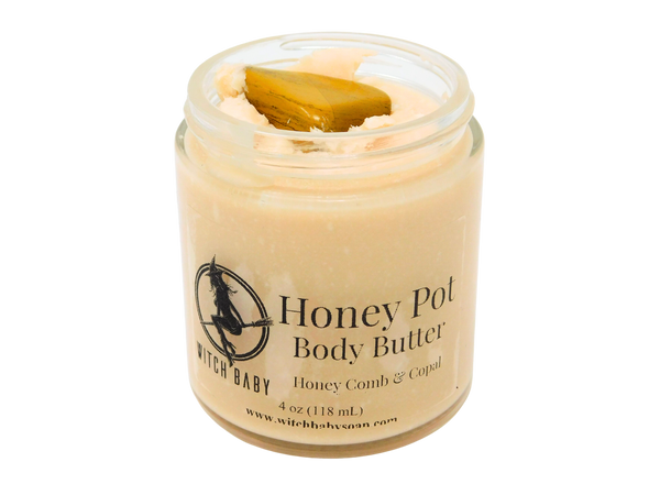 Honey colored body butter in 8 oz glass jar. Topped with yellow jasper. Label says Honey pot body butter honey comb and copal