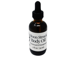 2 oz body oil packaged in a brown glass dropper bottle with a white label that reads: Moonstruck Body Oil. Wormwood & Pomegranate. 