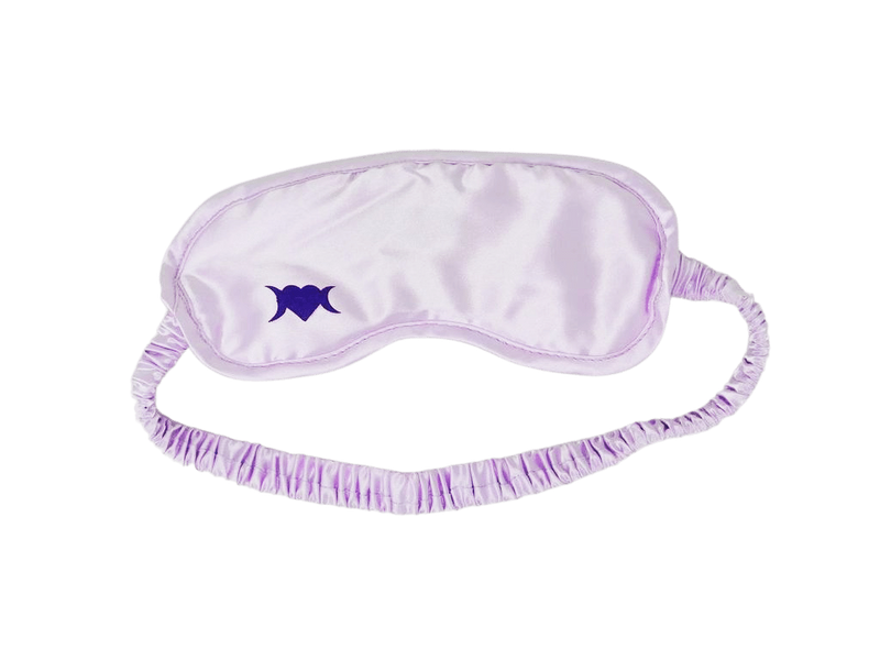 Photo of light lilac colored sleep mask with a symbol on the bottom left corner that is a heart with two crescent moons.
