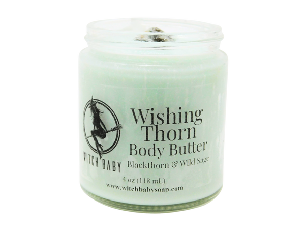 A sage green colored body butter packaged in a 4 oz glass jar with a label that reads: Wishing Thorn Body Butter. Blackthorn & Wild Sage.
