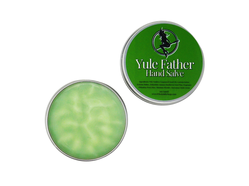 Yule Father Hand Salve pictures on white background with lid off and displayed beside it. Moisturizing holiday evergreen colored salve is packaged in a tin container. Green label on lid reads Yule Father hand Salve with ingredients.